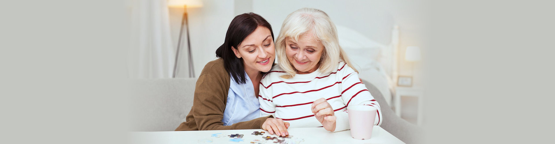 middle aged woman playing puzzles with an elderly woman